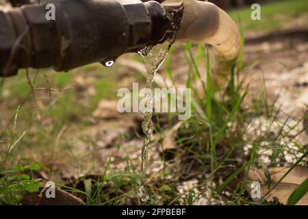 L'acqua perde da un tubo e gocciola sotto su la terra Foto Stock