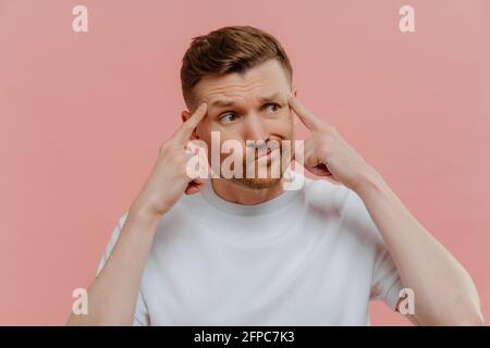 Giovane uomo che pensa a qualcosa e tiene le dita sulla sua templi Foto Stock