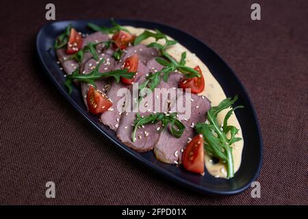 vista dall'alto su affettature di carne con rucola, pomodori e formaggio. Foto Stock