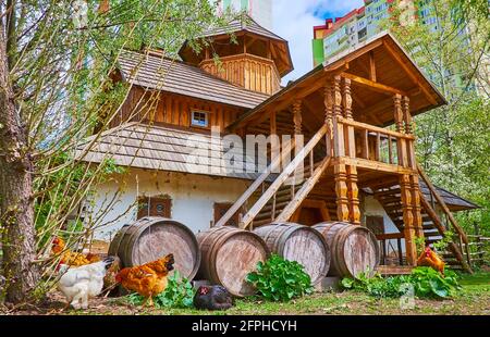 La costruzione di Cossack militare Chancery con vecchi barili e galline pascolanti di fronte ad esso, Mamajeva Sloboda Cossack Village scansen, Kyiv, Ucraina Foto Stock