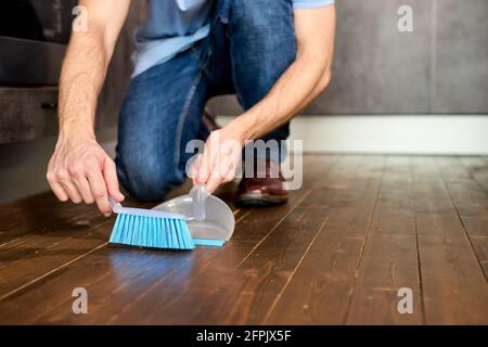 Uomo spazzare polvere con spazzolone su Dustpan, concetto di pulizia, primo  piano foto. Focus su Blue Brroom per la pulizia Foto stock - Alamy