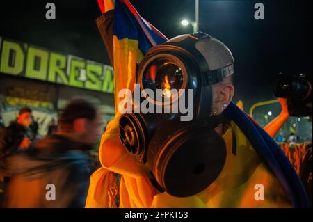 Un dimostrante che usa una maschera a gas solleva una bandiera nazionale colombiana mentre i dimostranti si sono riuniti allo stadio El Campin Futball per protestare contro il torneo di Copa America, e i casi di brutalità della polizia che hanno portato ad almeno 40 morti dall'inizio delle proteste 4 settimane fa. A Bogotà, Colombia, il 19 maggio 2021. Foto Stock