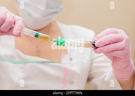 Lo specialista preleva il plasma ematico dalla provetta utilizzando una siringa. Plasmolifting, cosmetologia medica Foto Stock