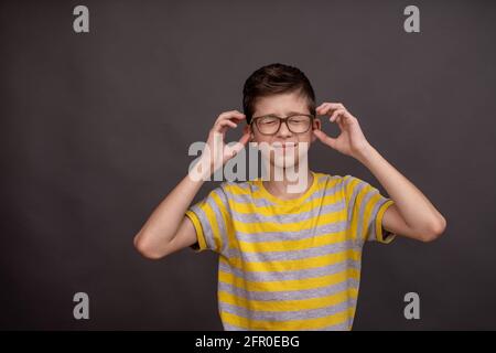 un ragazzo adolescente con gli occhiali ha un mal di testa. mock up Foto Stock