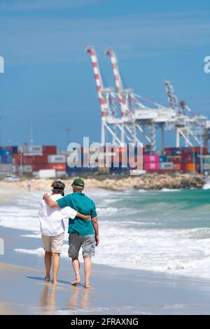 Coppie mature passeggiata lungo Port Beach vicino Fremantle con porto in background. Foto Stock