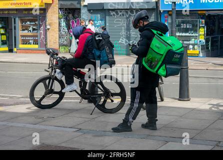 Londra. UK- 05.18.2021: Giovani uomini che lavorano come piloti autonomi per le società di ordinazione di alimenti online in attesa del loro prossimo avviso di lavoro. Foto Stock