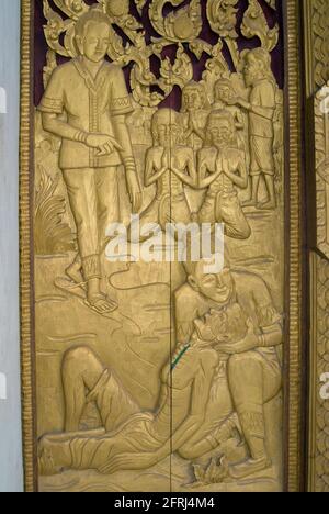 Porta decorativa con scultura in oro di persona morente, Wat Hai Sok Tempio, Vientiane, Lao Foto Stock