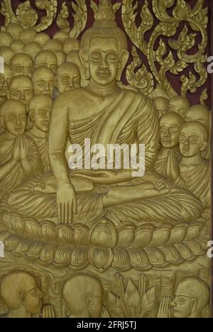 Porta decorativa con scultura in oro di Buddha circondata da monaci e discepoli, Wat Hai Sok Tempio, Vientiane, Lao Foto Stock