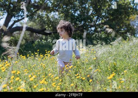 Giovane bambina che gioca all'aperto, sola in natura Foto Stock