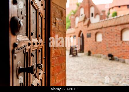 Vecchia porta in legno aperta con motivi intagliati e pomolo in metallo in un castello medievale Foto Stock