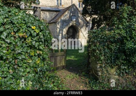 Antico cancello di legno in un muro di edera sopravvolta che conduce alla chiesa di Santa Maria nel villaggio di Haversham, Buckinghamshire, Regno Unito Foto Stock