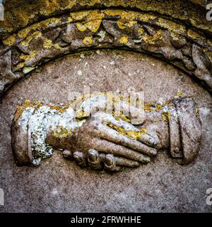 Una pietra scolpita stretta di mano da una lapide in un cimitero di campagna. Foto Stock