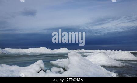Ghiacciai innevati in una soleggiata giornata invernale in riva al mare. Tutto è congelato, il cielo è molto blu. Atmosfera drammatica. Foto Stock