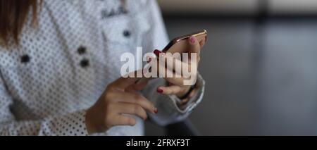 Inquadratura ritagliata delle mani femminili utilizzando lo smartphone su sfondo sfocato Foto Stock