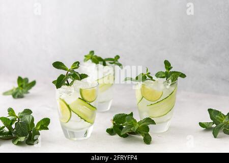 Bevande rinfrescanti fredde con lime e cetrioli, bevande ghiacciate estive e menta verde fresca, bicchieri con acqua al limone Foto Stock