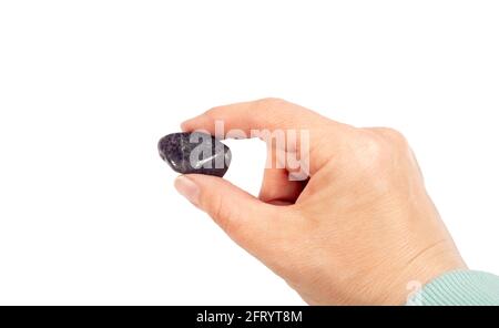 Donna che tiene il colore viola tumbled Iolite o gemma cordierite in mano, isolato su sfondo bianco, molto spazio di copia. Chiamato anche 'zaffiro-acqua Foto Stock