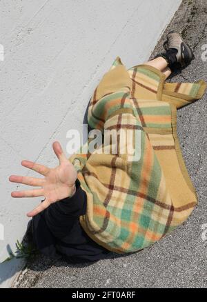 povero uomo sotto una coperta che alza la mano a. Dica abbastanza degli abusi e della sua situazione di estremo povertà Foto Stock