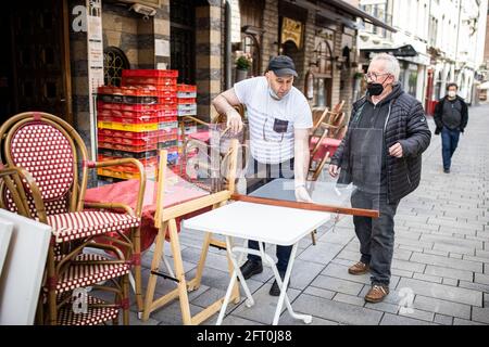 Duesseldorf, Germania. 21 Maggio 2021. Il ristoratore Saraya (l) e un dipendente allestiscono tavoli e divisori di fronte al suo ristorante nell'Altstadt. Dopo un mese di pausa forzata, i ristoratori di Düsseldorf potranno accogliere nuovamente gli ospiti a partire da venerdì. Come in altri comuni della NRW, questo vale solo per l'area esterna. Credit: Marcel Kusch/dpa/Alamy Live News Foto Stock