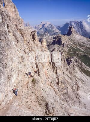 Italia. L'immagine è di un gruppo di scalatori che salgono lungo il sentiero protetto di Via Ferrata sul Paternkofel [Monte Paterno] guardando verso il pinnacolo del Toblinger Knoten Spitze vicino alle famose tre Torri, Conosciuto in tedesco come Drei Zinnen, ma più poeticamente chiamato in italiano come le tre Cime di Laverado, situato nella regione orientale di Sesto-Sesto delle Dolomiti italiane. Durante la prima guerra mondiale, l'esercito austriaco ha installato un cannone da campo sulla cima del piccolo picco in modo che la conchiglia gli italiani a poco più di un chilometro di distanza. Gli arrampicatori sono in realtà sulla linea di fronte austriaca Foto Stock