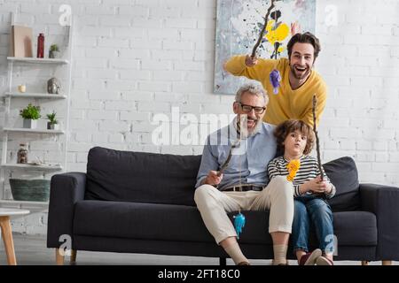 Felici i genitori con il ragazzo che tiene canne da pesca con pesci giocattolo Foto Stock