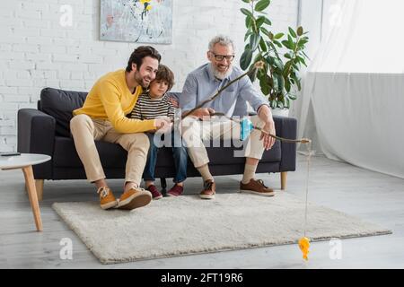 Genitori allegri e bambini che giocano a pescare a casa Foto Stock