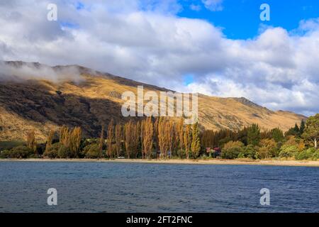 Vista di Kingston, una piccola città sul lago Wakatipu, Nuova Zelanda, dall'acqua. Fotografato in autunno Foto Stock