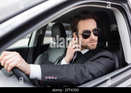 protezione con bearded in occhiali da sole e tuta per regolare l'auricolare di sicurezza auto Foto Stock