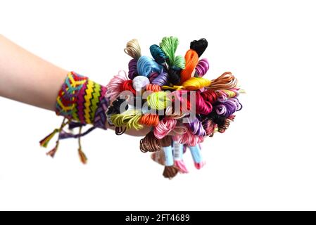 Molti fili di ricamo per bracciali di amicizia in mano. Mano femminile con braccialetti fatti a mano sui polsi. Sfondo bianco con spazio per la copia Foto Stock