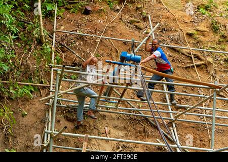 I lavoratori rinforzano la montagna per evitare frane sulla strada. Foto Stock