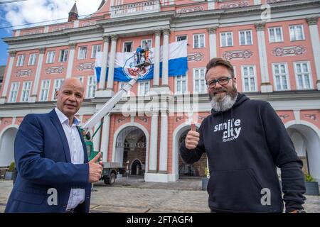 Rostock, Germania. 21 Maggio 2021. Claus Ruhe Madsen (r), sindaco di Rostock e il suo vice Chris Müller-von Wrycz Rekowski (l) si trovano di fronte al municipio con la bandiera della squadra di calcio F.C. Hansa. Il candidato alla promozione FC Hansa Rostock, attualmente secondo al tavolo, affronterà VfB Lübeck nel finale di stagione della 3a Football League. Credit: Jens Büttner/dpa-Zentralbild/dpa/Alamy Live News Foto Stock