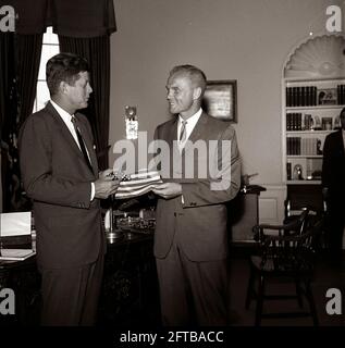 Il presidente John F. Kennedy riceve un dono di una bandiera americana dall'astronauta tenente colonnello John H. Glenn, Jr. (A destra); il Lt. Colon ha portato la bandiera nella sua tuta spaziale durante il suo volo orbitale a bordo del Mercury-Atlas 6, noto anche come amicizia 7. Sullo sfondo c'è l'assistente speciale del presidente, Kenneth P. o'Donnell. Ufficio ovale, Casa Bianca, Washington, D.C. Foto Stock