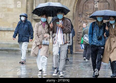 Bath, Somerset, Regno Unito. 21 Maggio 2021. Un uomo e una donna che riparano sotto un ombrello sono raffigurati fuori Bath Abbey come forti docce pioggia fanno il loro modo attraverso il Regno Unito. Credit: Lynchpics/Alamy Live News Foto Stock