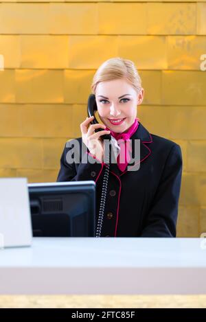 Hotel receptionist con telefono sul banco anteriore Foto Stock