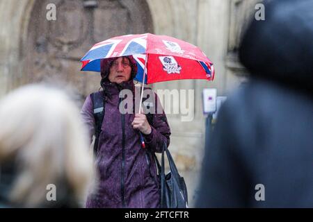 Bath, Somerset, Regno Unito. 21 Maggio 2021. Una donna che ripara sotto un ombrello è raffigurata fuori Bath Abbey come forti docce a pioggia fanno il loro modo attraverso il Regno Unito. Credit: Lynchpics/Alamy Live News Foto Stock