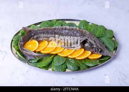 Sterlet cotta al forno (storione) con spinaci e arance. Cucina russa. Primo piano. Foto Stock