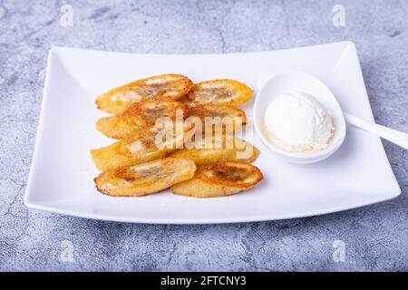 Banane fritte con miele, cannella, caffè e gelato. Primo piano. Foto Stock
