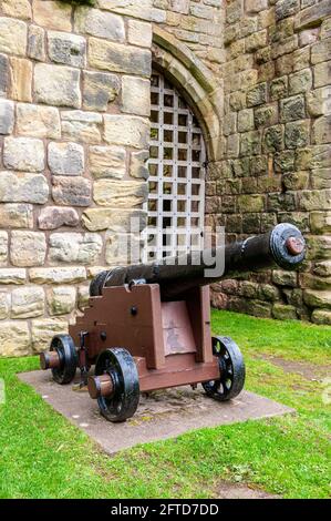 Un cannone a nove passerelle di HMS George, affondato nell'agosto 1732, si trova su una carrozza di legno di fronte ad una torre di etal Castle gatehouse Foto Stock