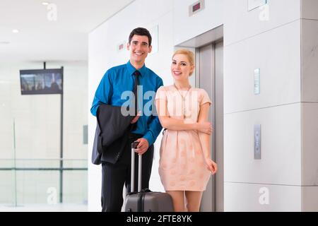 Felice coppia che aspetta l'ascensore dell'hotel o l'ascensore Foto Stock