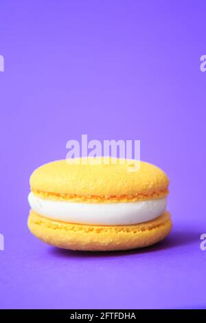 Yellow Cake macaron o macaroon su sfondo viola. Biscotti colorati alle mandorle. Primo piano sulla torta di macaroon francese. Macaroni su sfondo colorato Foto Stock