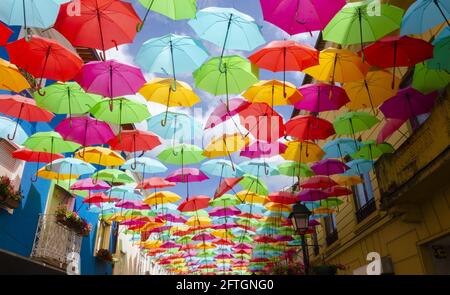 Ombrelli colorati sotto un cielo blu vicino al cielo di Umbrella Progetto su Rua Luís de Camões Foto Stock