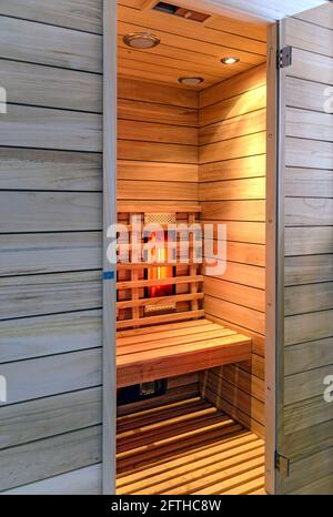vista su una cabina a infrarossi in legno con elementi riscaldanti incandescenti e aprire lo sportello Foto Stock