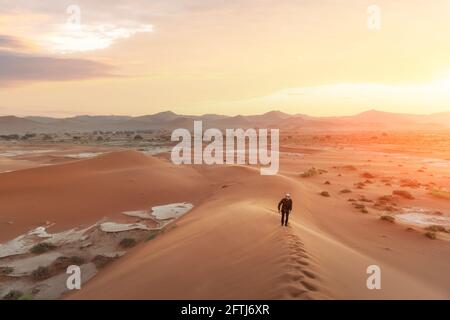 Uomo singolo su dune alte nel deserto del Namib Foto Stock