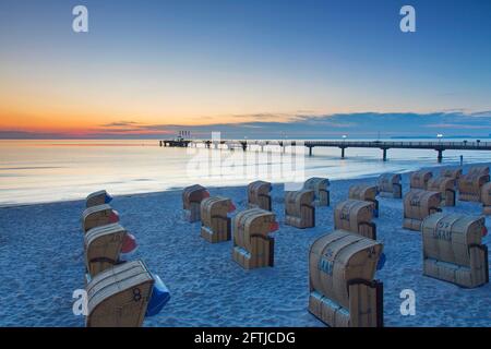 Sedie da spiaggia in vimini con tetto e molo / molo in legno presso la località balneare di Scharbeutz, Ostholstein lungo la baia di Lübeck, Schleswig-Holstein, Germania Foto Stock