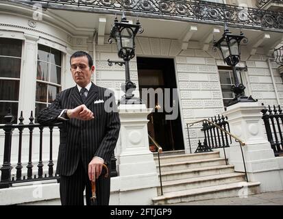 Gentiluomo che indossa una tuta in attesa di un taxi fuori dai Bianchi Gentleman Club St James Street Londra W1 Foto Stock