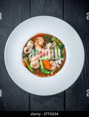 Un piatto di Thai Rat Na Noodle con frutti di mare, broccoli cinesi e salsa addensata Foto Stock