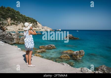 Una donna turistica con cappello goda Agios Nikitas villaggio sull'isola Ionica di Lefkas, Grecia Foto Stock