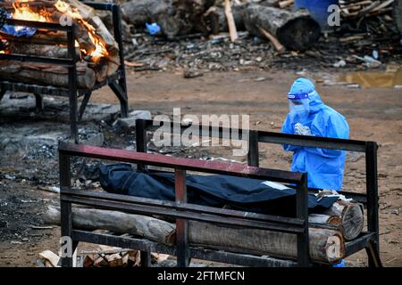 Bengaluru, Select, India. 10 maggio 2021. (NOTA EDITORÃ-S: Immagine della morte).UN membro della famiglia paga gli ultimi omaggi alla parente prima di cremare la vittima del Covid-19 in una cava.la seconda ondata della pandemia del Covid-19 ha catturato il sistema sanitario del paese su un piede posteriore, in quanto il numero di vittime sta aumentando esponenzialmente, causando crematori di operare giorno e notte. Bengaluru ha convertito una delle sue cave inutilizzate a Giddenahalli, situata in periferia, in un crematorio aperto. Credit: Meghana Sastry/SOPA Images/ZUMA Wire/Alamy Live News Foto Stock