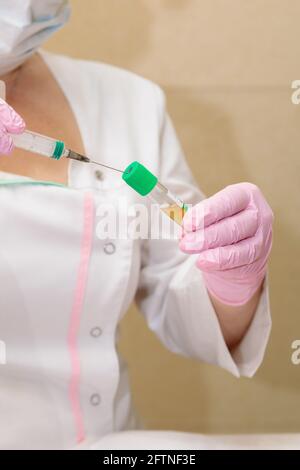 Lo specialista preleva il plasma ematico dalla provetta utilizzando una siringa. Plasmolifting, cosmetologia medica Foto Stock