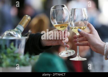 Duesseldorf, Germania. 21 Maggio 2021. Le donne brindano con vino bianco ad un tavolo nell'area esterna di un ristorante. Dopo mesi di pausa forzata, i ristoratori di Düsseldorf sono autorizzati ad accogliere nuovamente gli ospiti a partire dal venerdì. Come in altri comuni della NRW, questo vale solo per l'area esterna e in determinate condizioni. Credit: David Young/dpa/Alamy Live News Foto Stock