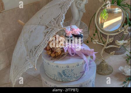 decorazioni in pizzo ombrello ancora vita. Bouquet di fiori secchi, in cima a scatole rotonde impilate con uno specchio, e altri oggetti di decorazione domestica. Foto Stock